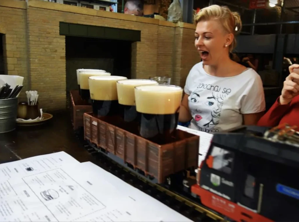 Kufle piwa dowożone do stolika kolejką w praskim pubie