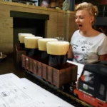 Kufle piwa dowożone do stolika kolejką w praskim pubie