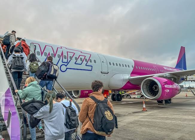 Pasażerowie wchodzący po schodach na pokład samolotu Wizz Air – środki WIZZ za rezerwacje na Booking.com